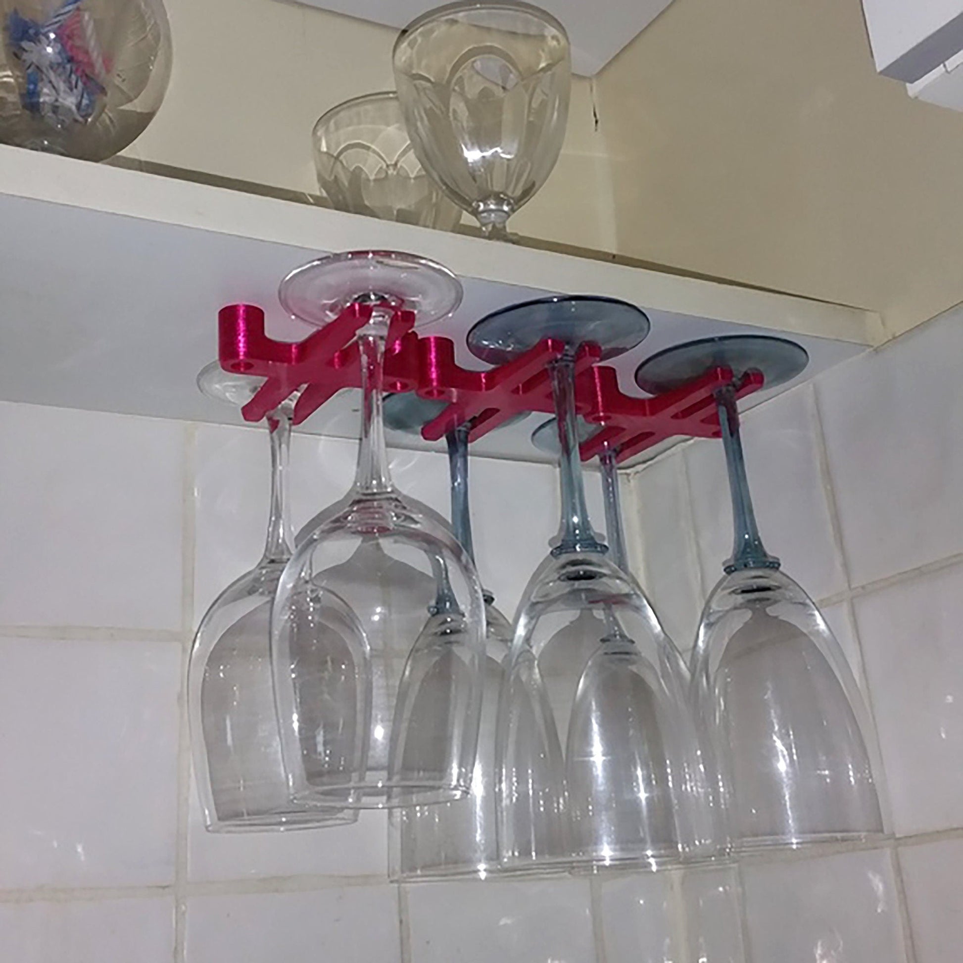 four wine glasses hanging from a shelf in a kitchen