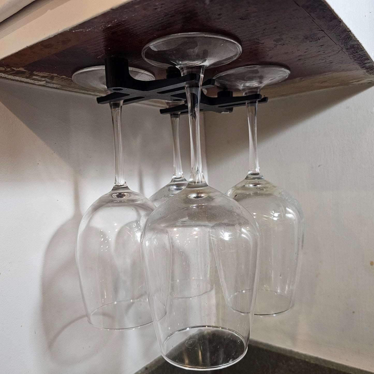 three wine glasses are hanging from a shelf