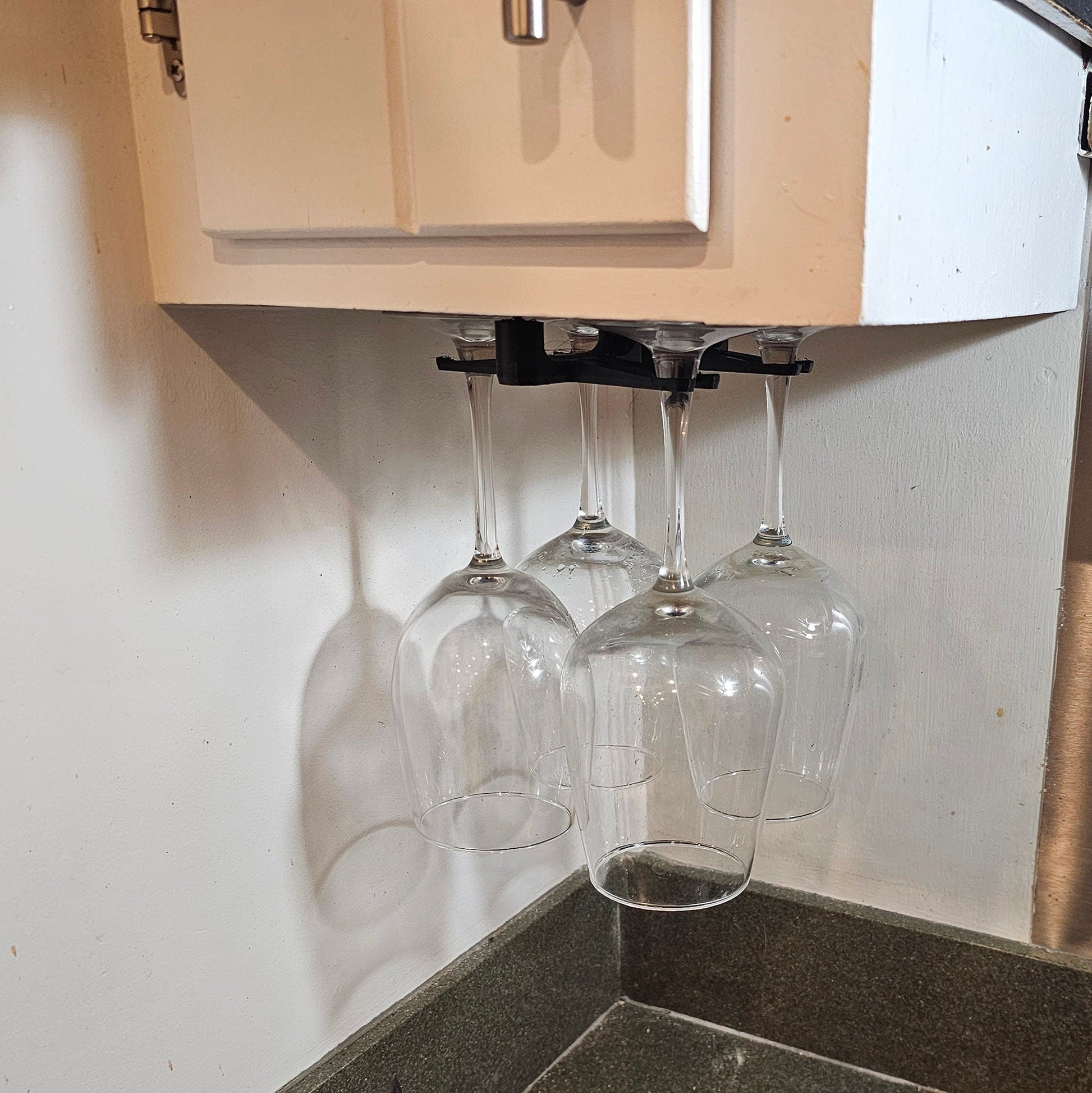 three wine glasses hanging from a kitchen wall