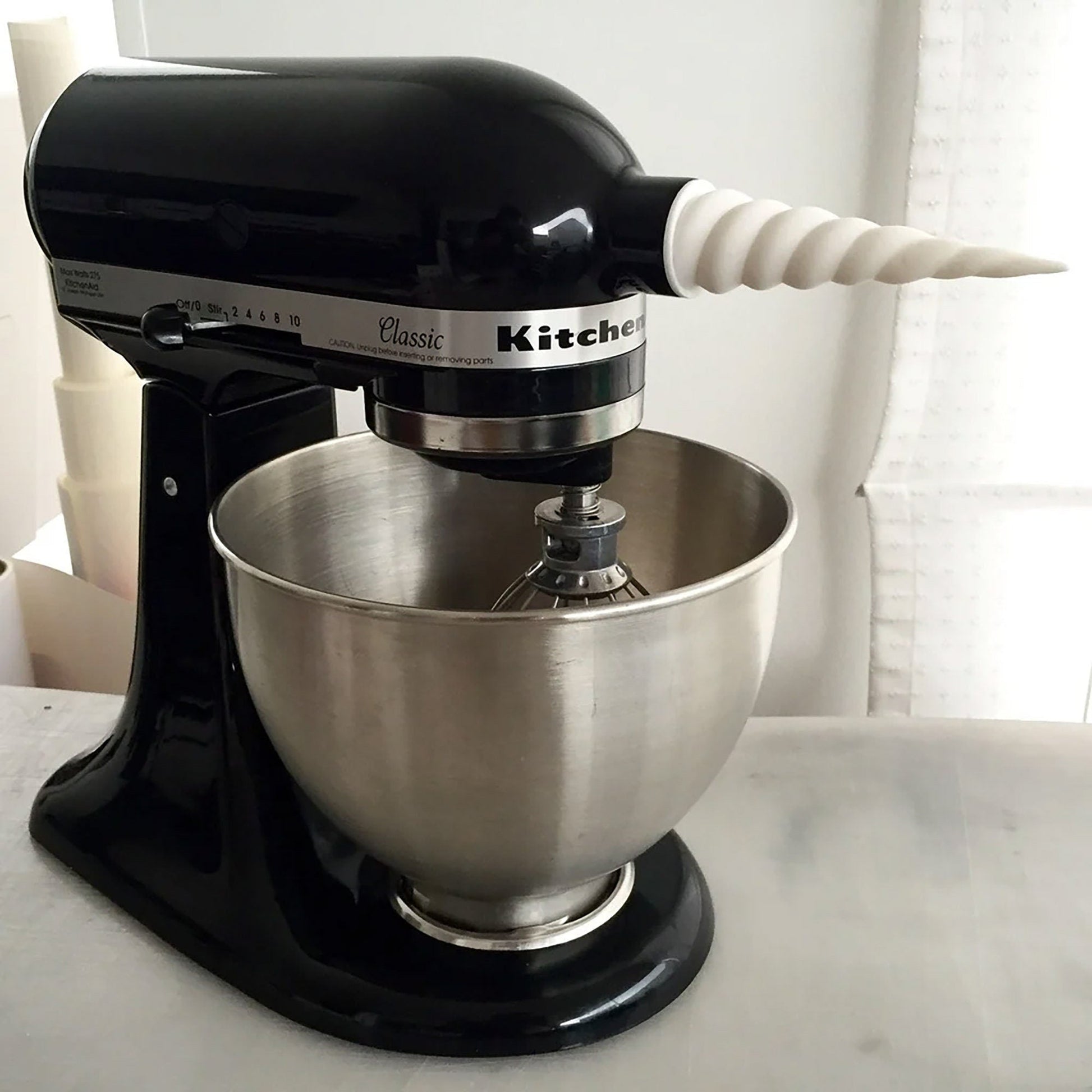 a black mixer with a white handle on a counter