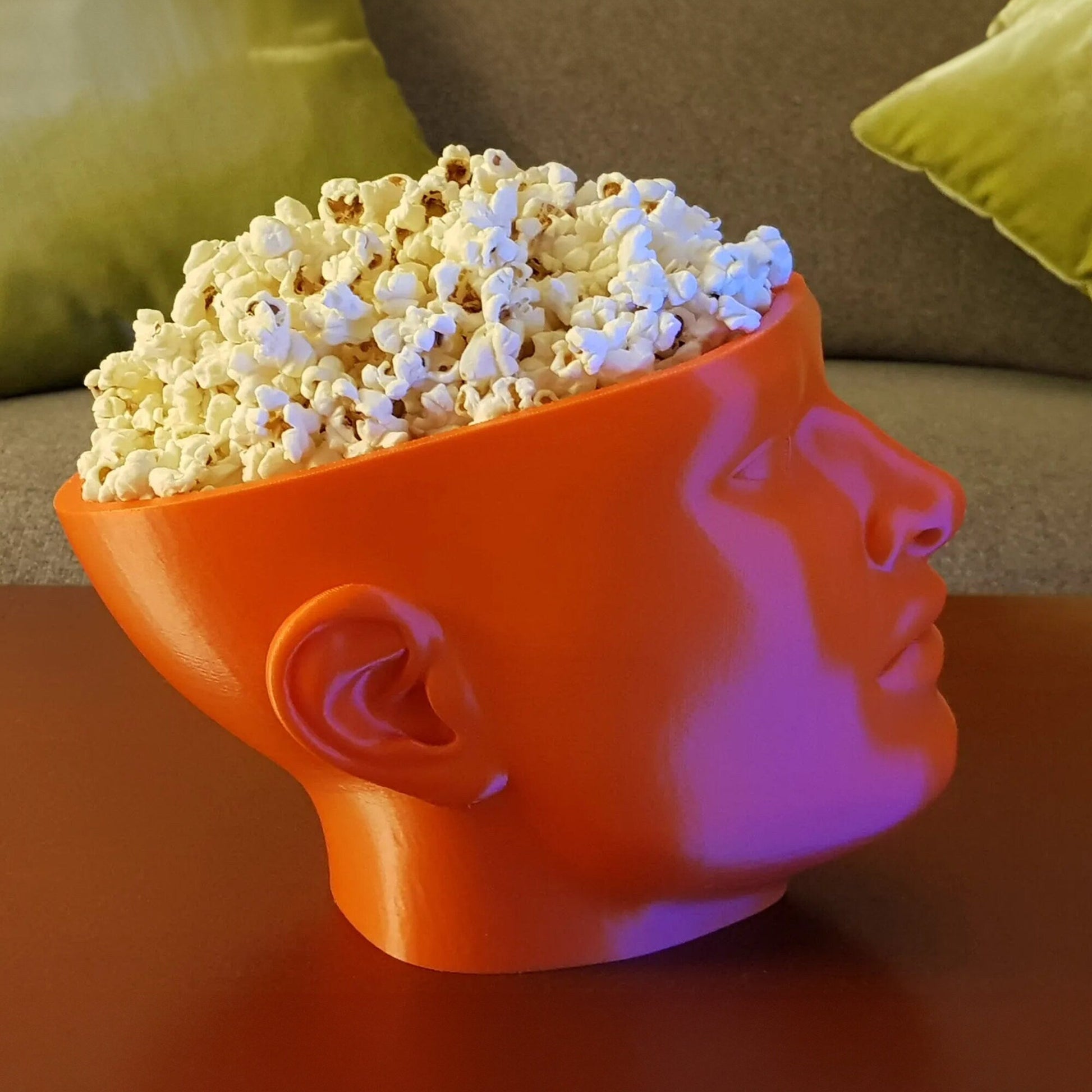 a large orange bowl filled with popcorn sitting on top of a table