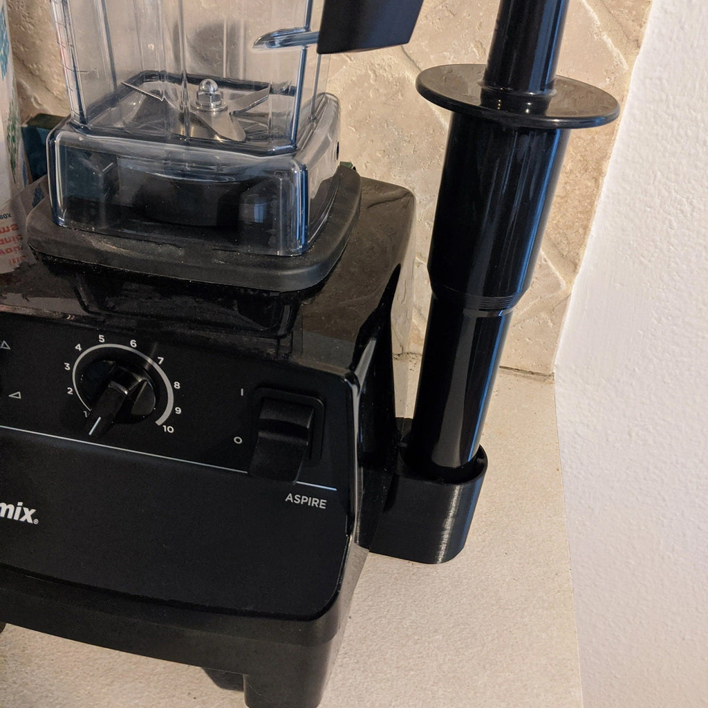 Side-mount tamper holder clipped to a Vitamix blender base, view 2