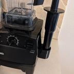 Side-mount tamper holder clipped to a Vitamix blender base, view 2