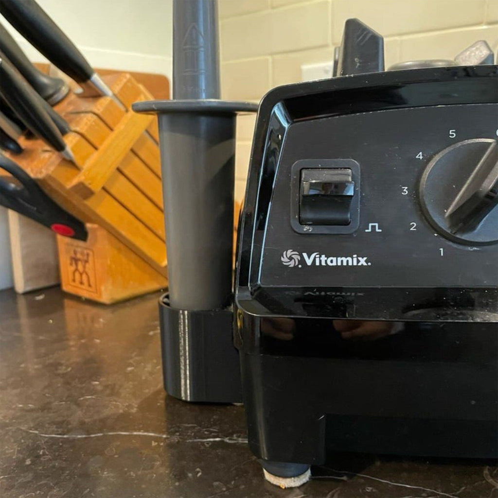 Side-mount tamper holder clipped to a Vitamix blender base, view 4