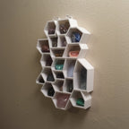 Honeycomb wall shelf displaying crystals and gemstones in hexagonal cells, view 2