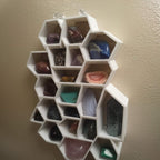 Honeycomb wall shelf displaying crystals and gemstones in hexagonal cells, view 3