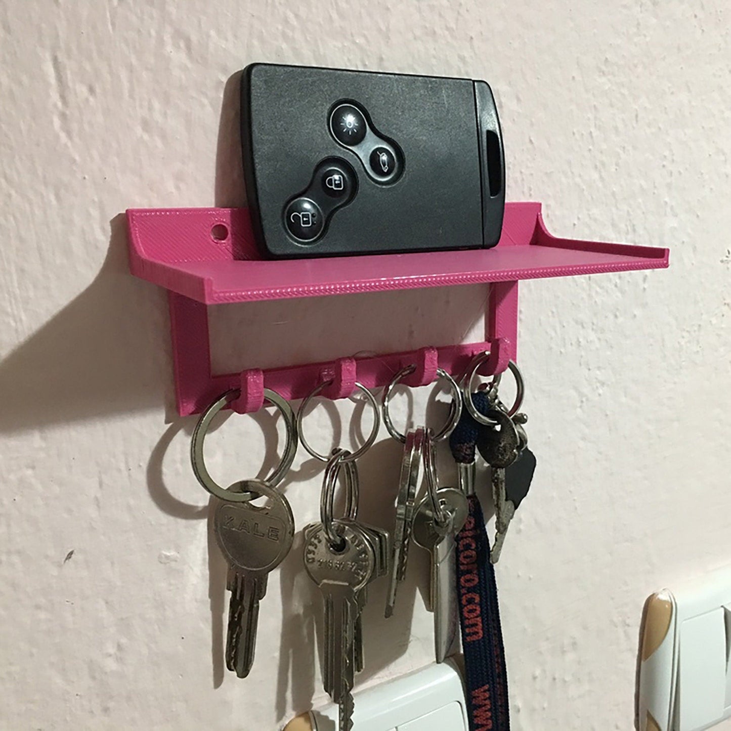 a pink shelf holding keys and a remote control