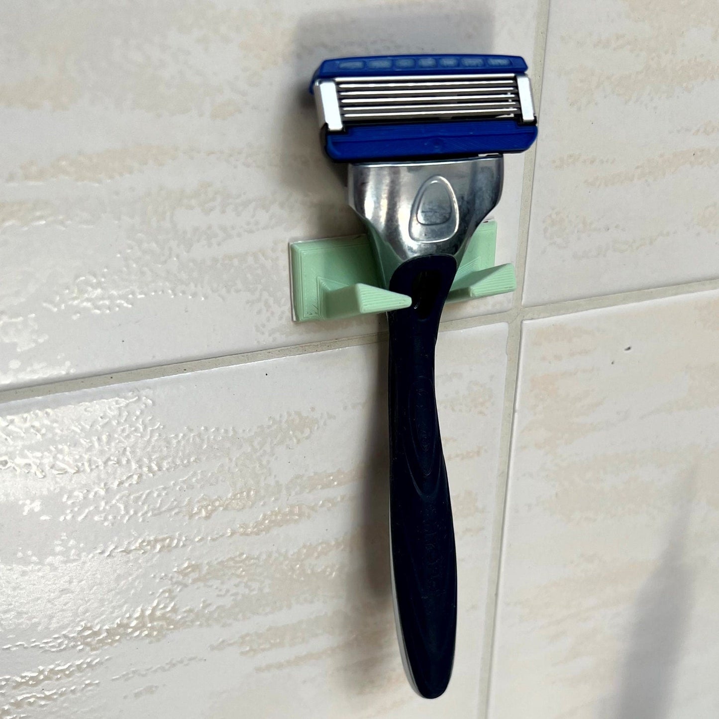 a toothbrush and a razor on a tile wall