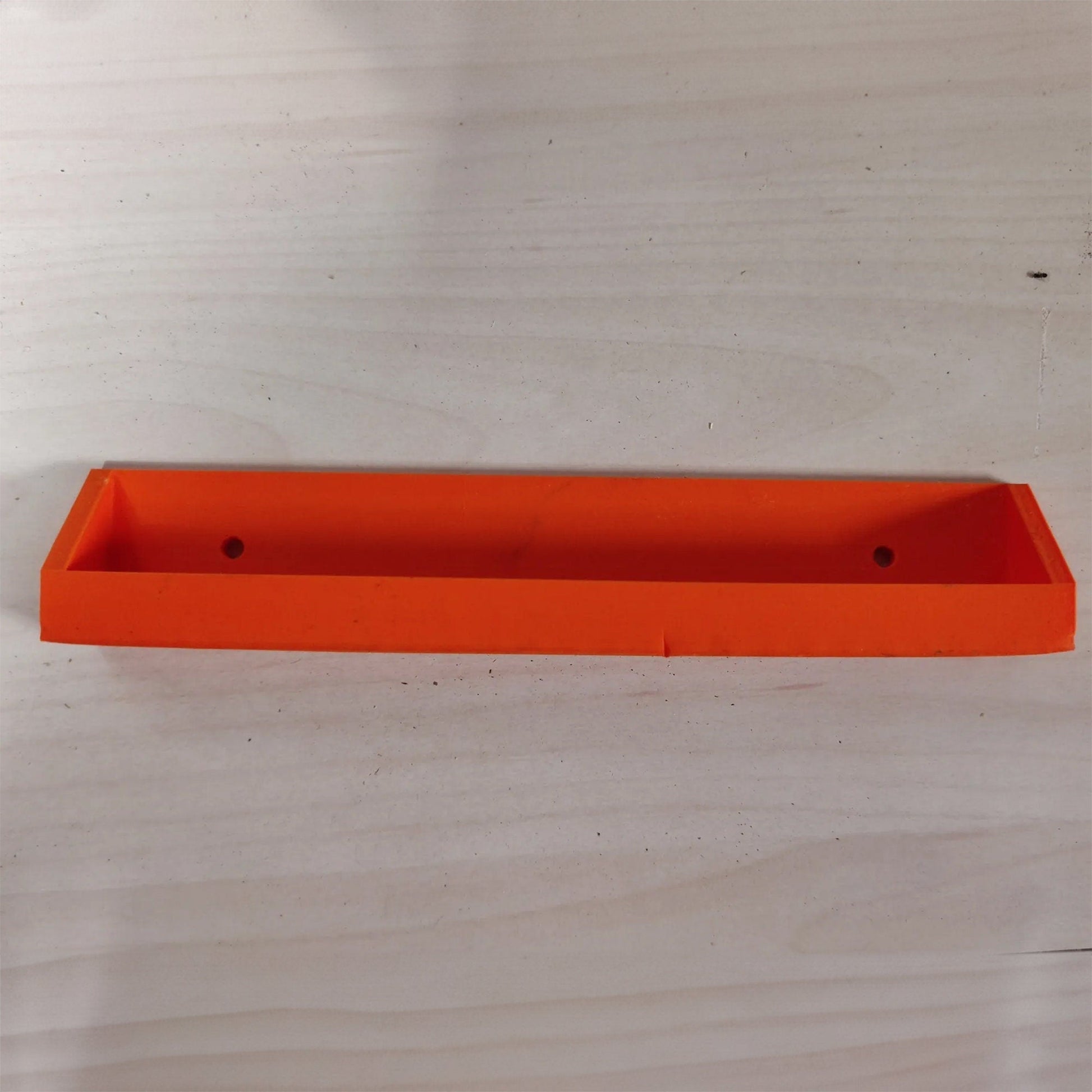 an orange plastic object on a wooden surface