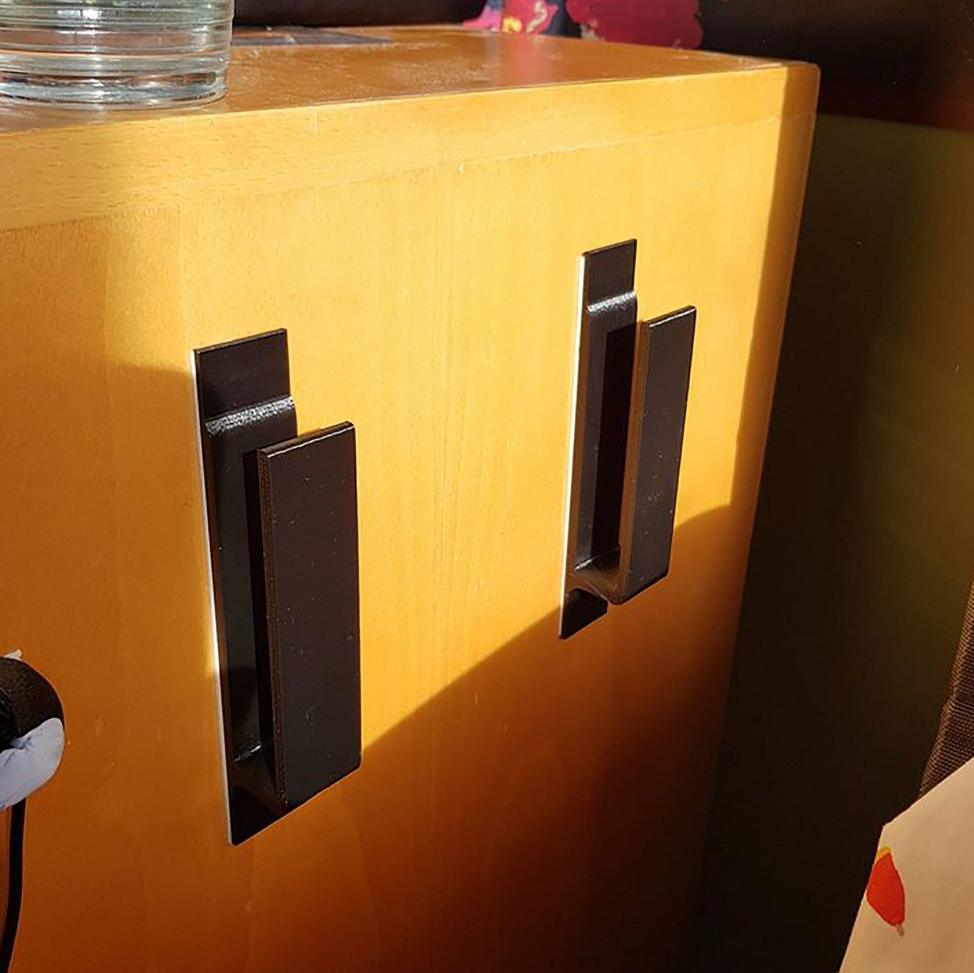 a close up of a yellow cabinet with two black handles