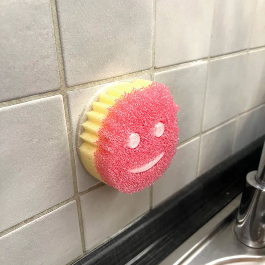 a smiley face scrubber hanging on the side of a wall