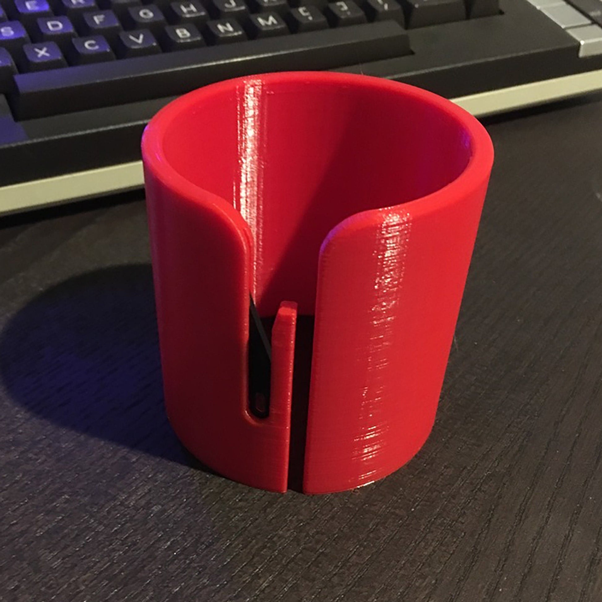 a red cup sitting on top of a desk next to a keyboard