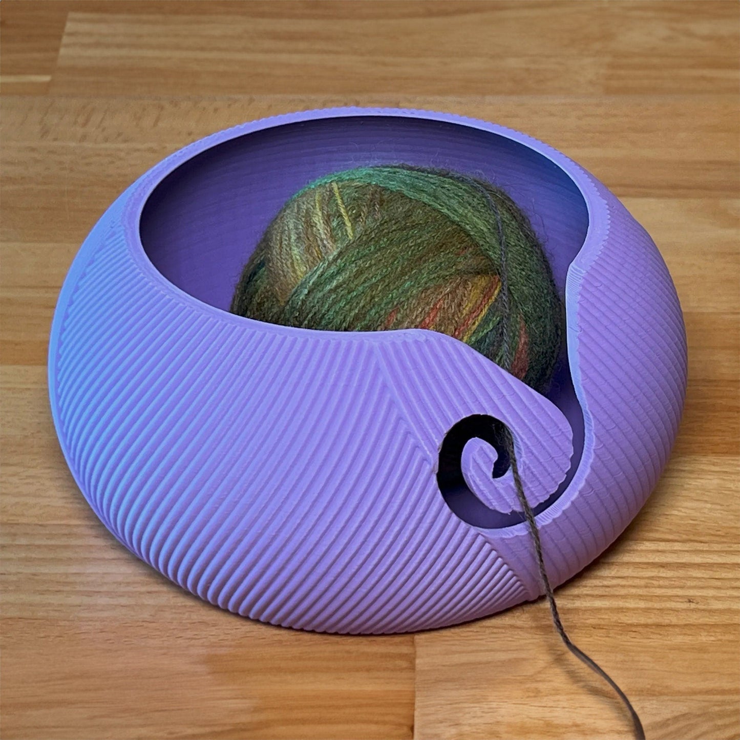 a ball of yarn sits in a purple bowl