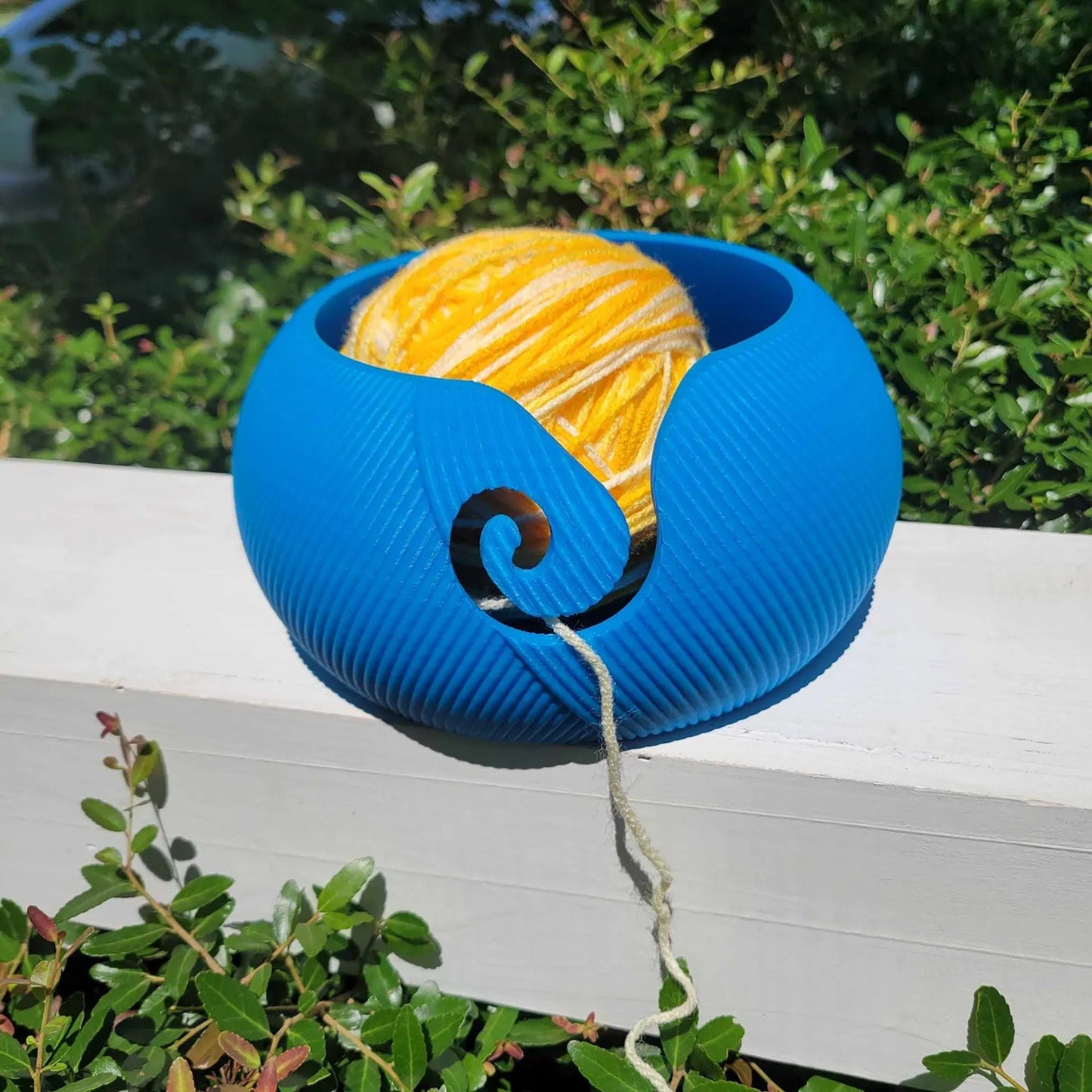 a blue and yellow object sitting on top of a white fence